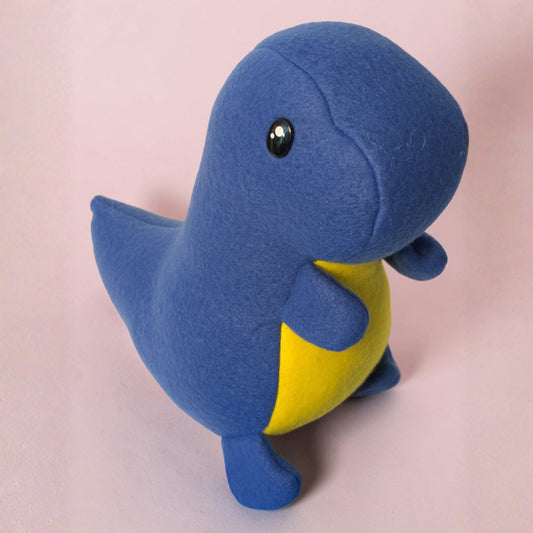 A small blue plush dinosaur toy with a yellow belly and black safety eyes, standing on a soft pink background.