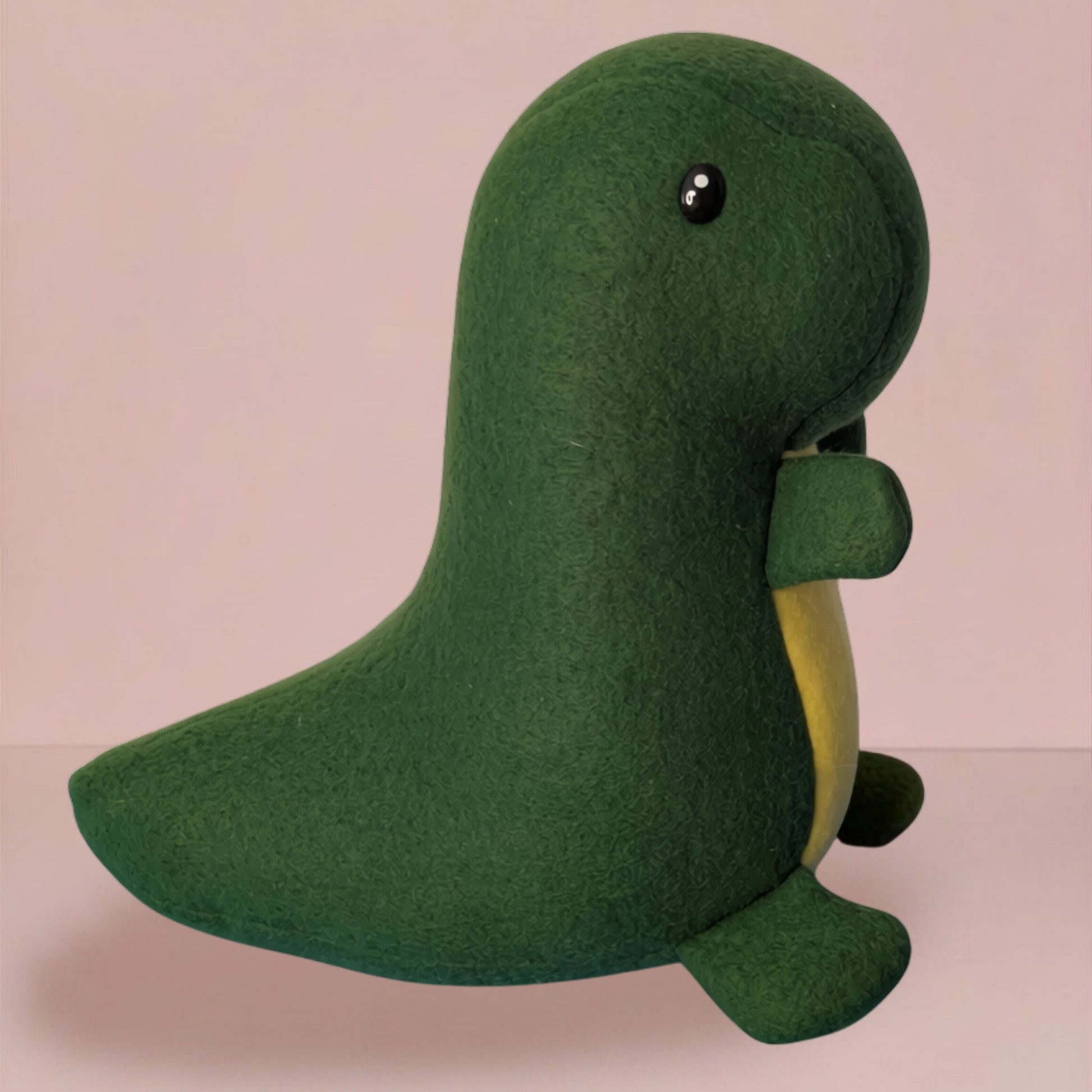 A green fleece dinosaur plush toy with a yellow belly and small black eyes, shown against a soft pink background.