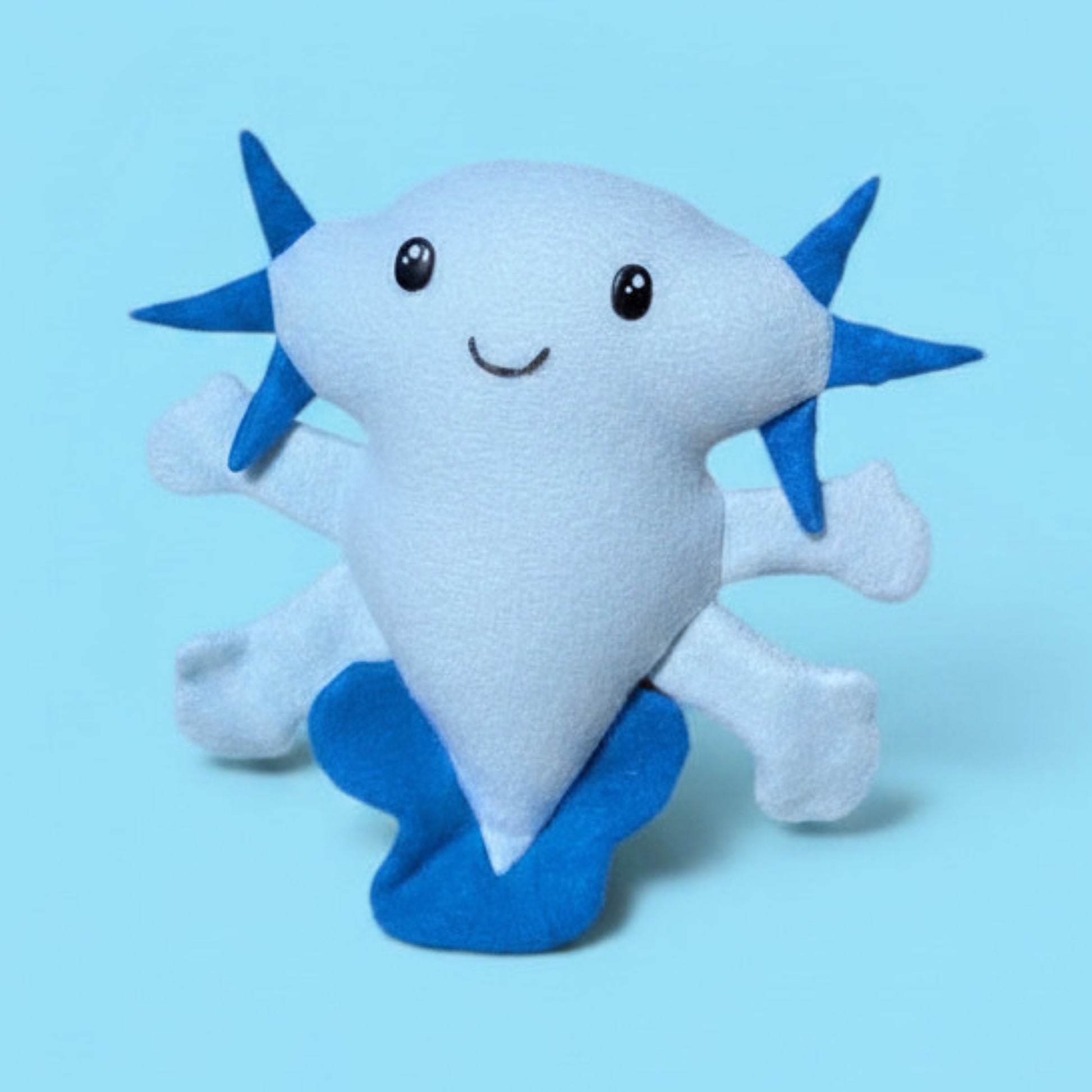 A blue fleece smiling Axolotl stuffed animal toy with a pale blue body and royal blue fins and gills.