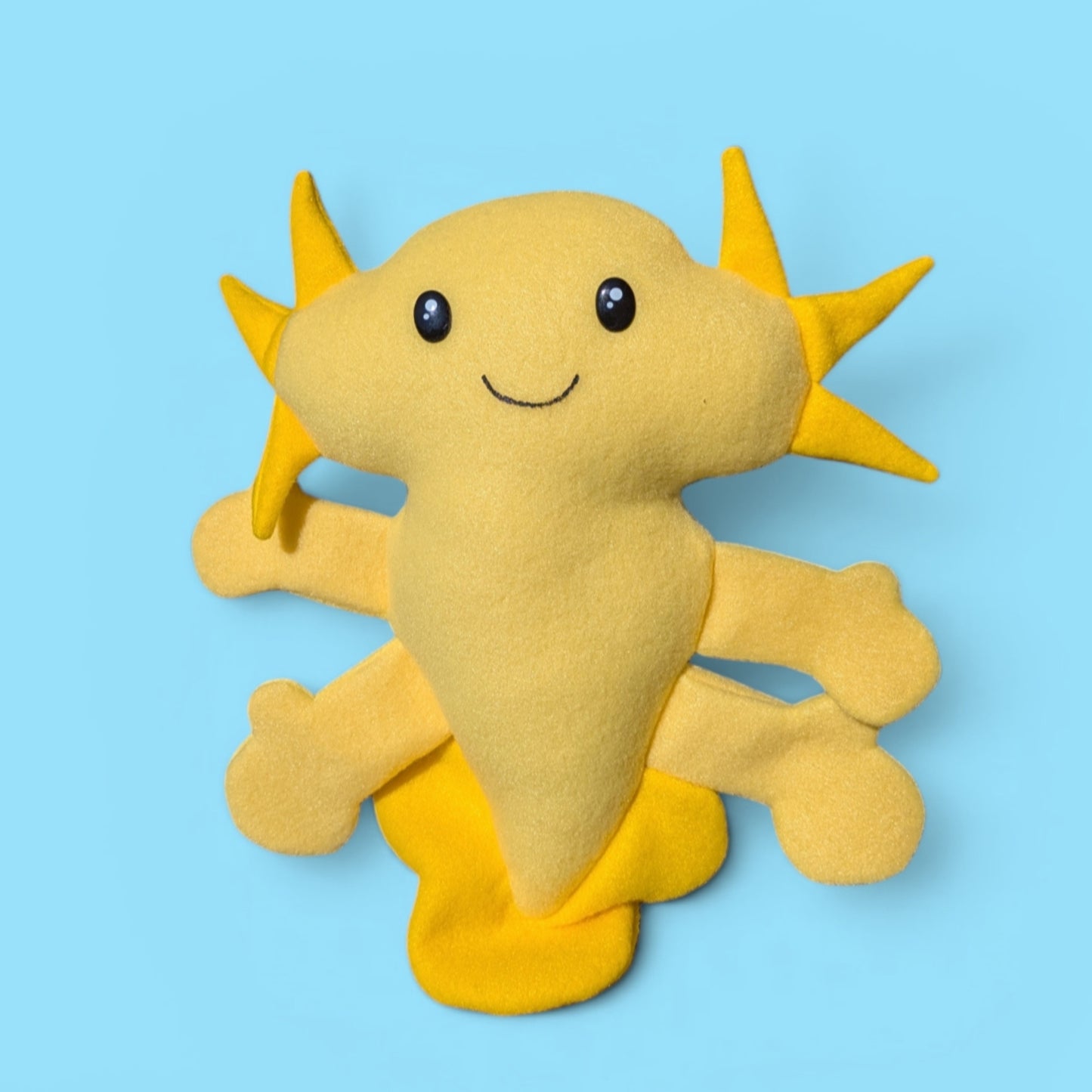 A yellow fleece axolotl plush toy with a pale yellow body and yellow fins and gills.