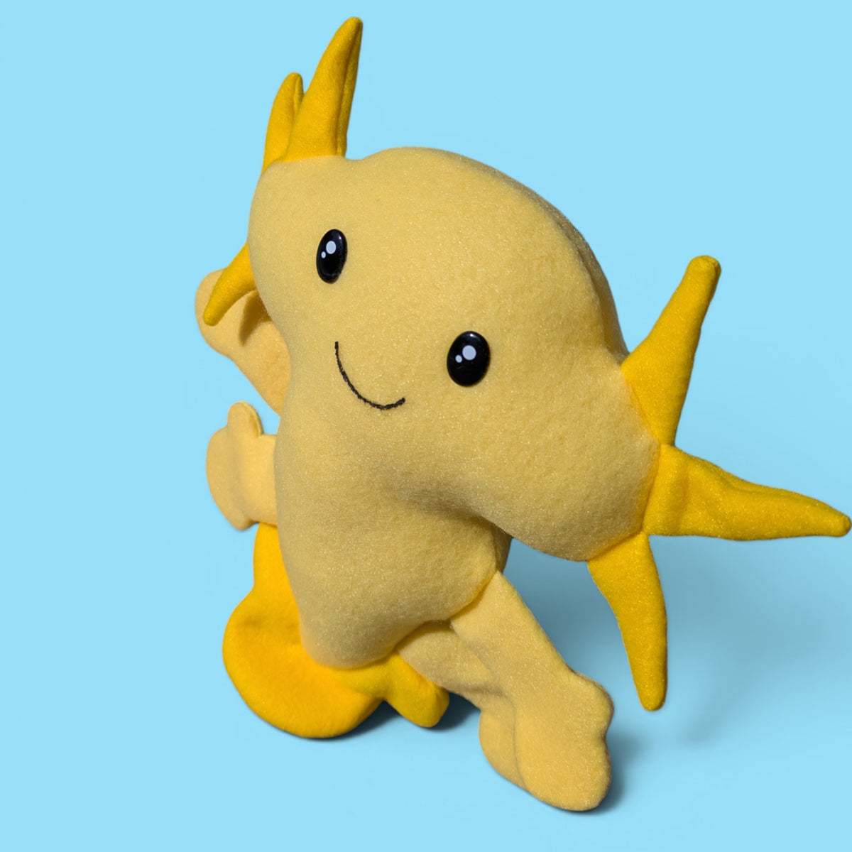 A yellow fleece axolotl plush toy with a pale yellow body and yellow fins and gills.