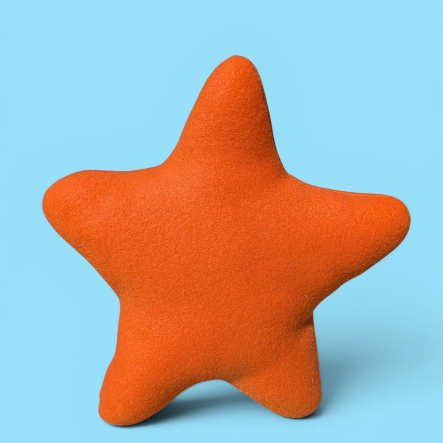 A close-up back profile of an orange fleece plush starfish toy with a simple set against a plain light gray background.