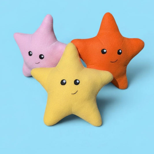 Three plush star-shaped stuffed animals in pink, orange, and yellow, each with felt eyes and a smile, arranged on a light blue background.