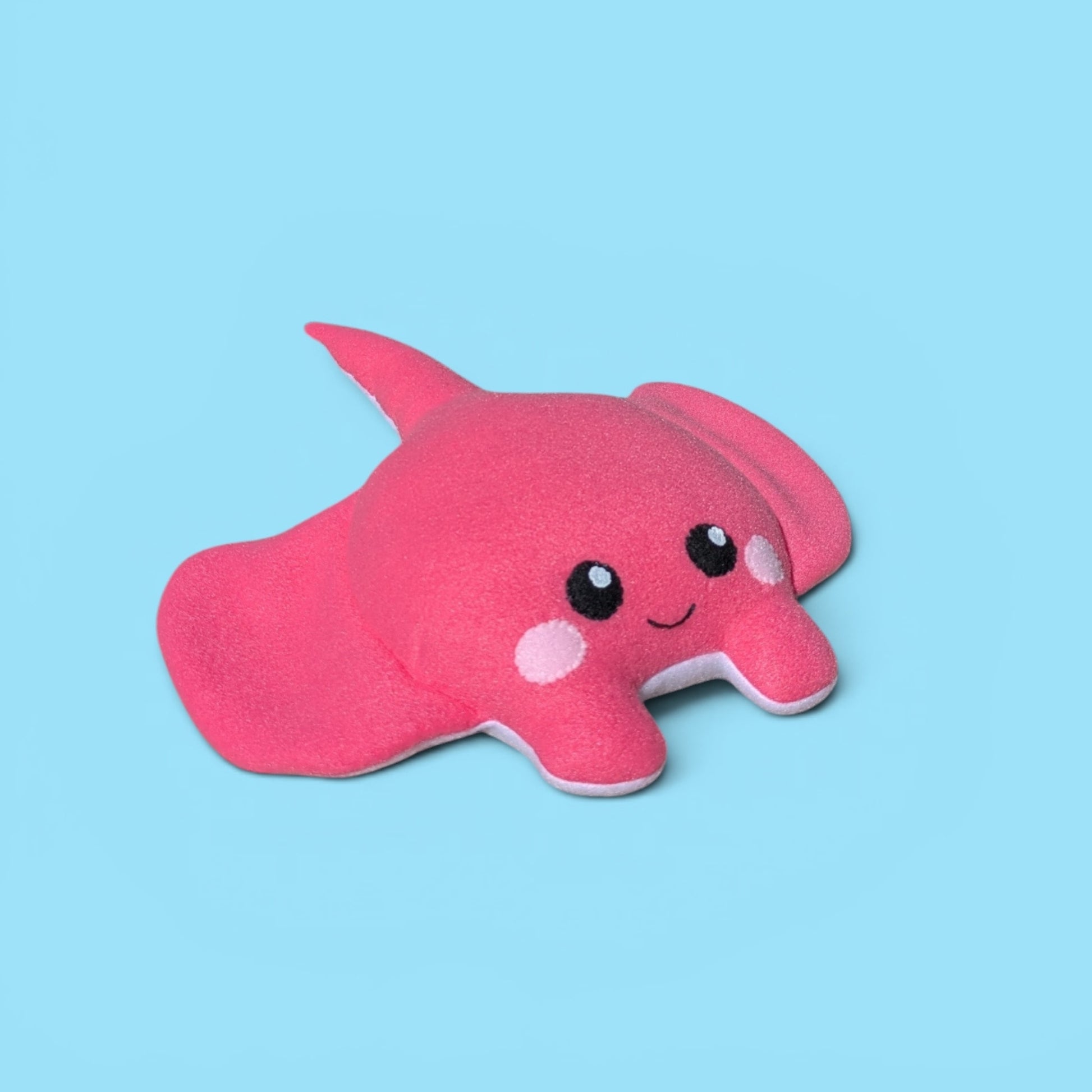 A fleece felt sea creature plush toy, shaped like a stingray with a smiling face, set against a solid light blue background.