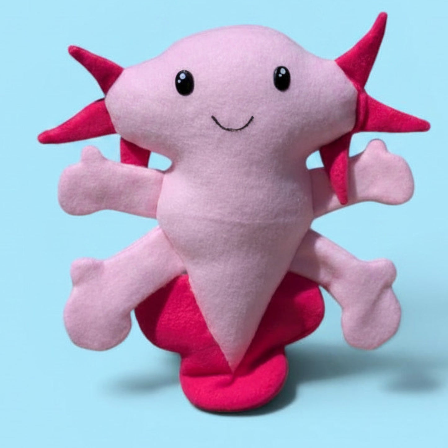 A plush fleece axolotl stuffed animal with light pink body and arms and hot pink gills and fins