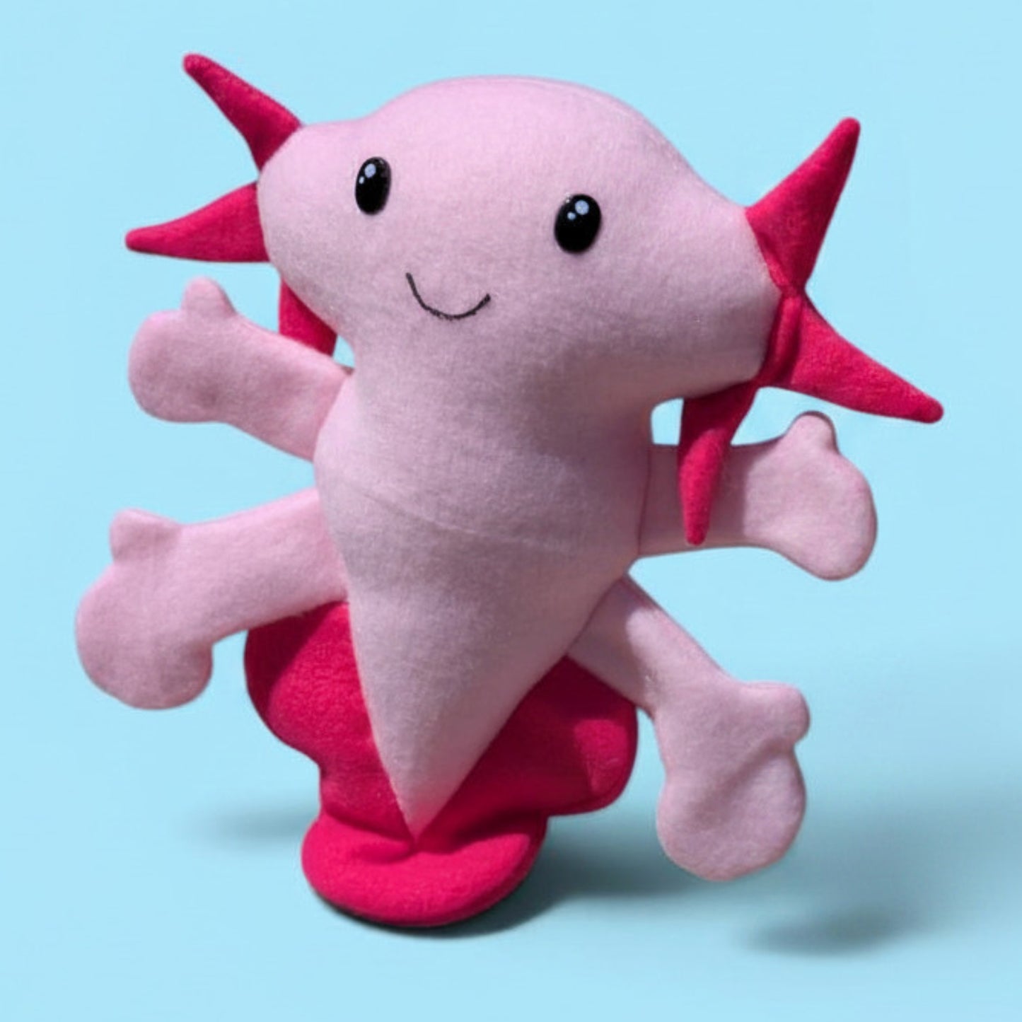 A pink and magenta plush toy shaped like a cartoon axolotl, shown against a solid light blue background.