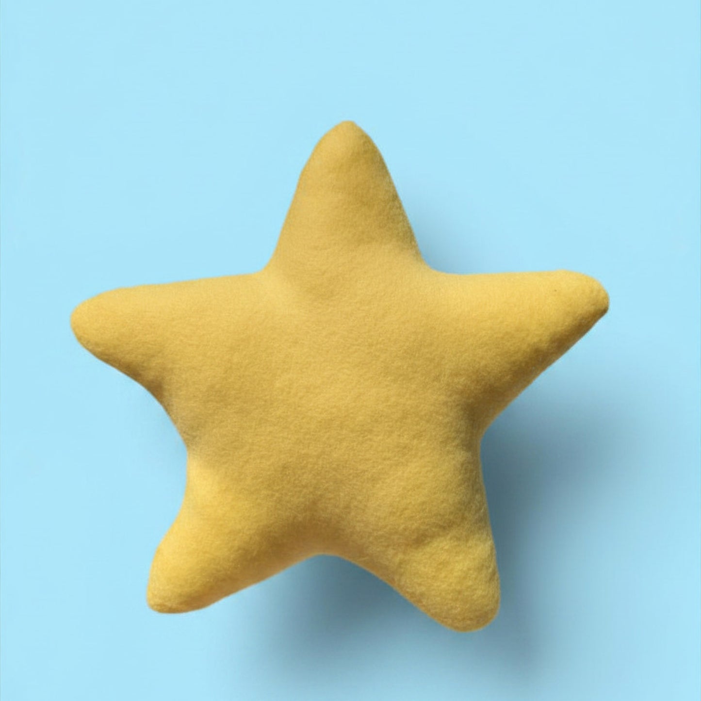 A yellow star-shaped plush pillow with a soft, fuzzy texture, centered against a solid light blue background.