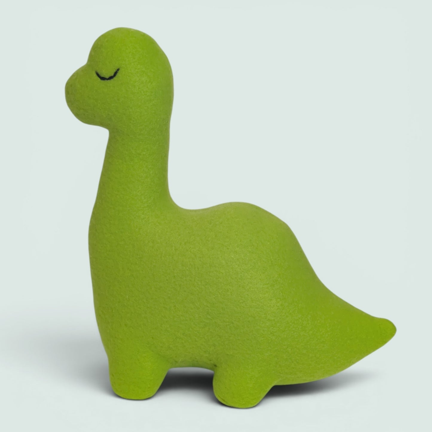 A bright lime green dinosaur fleece toy and simple black stitched closed eyes, shown on a light gray background.