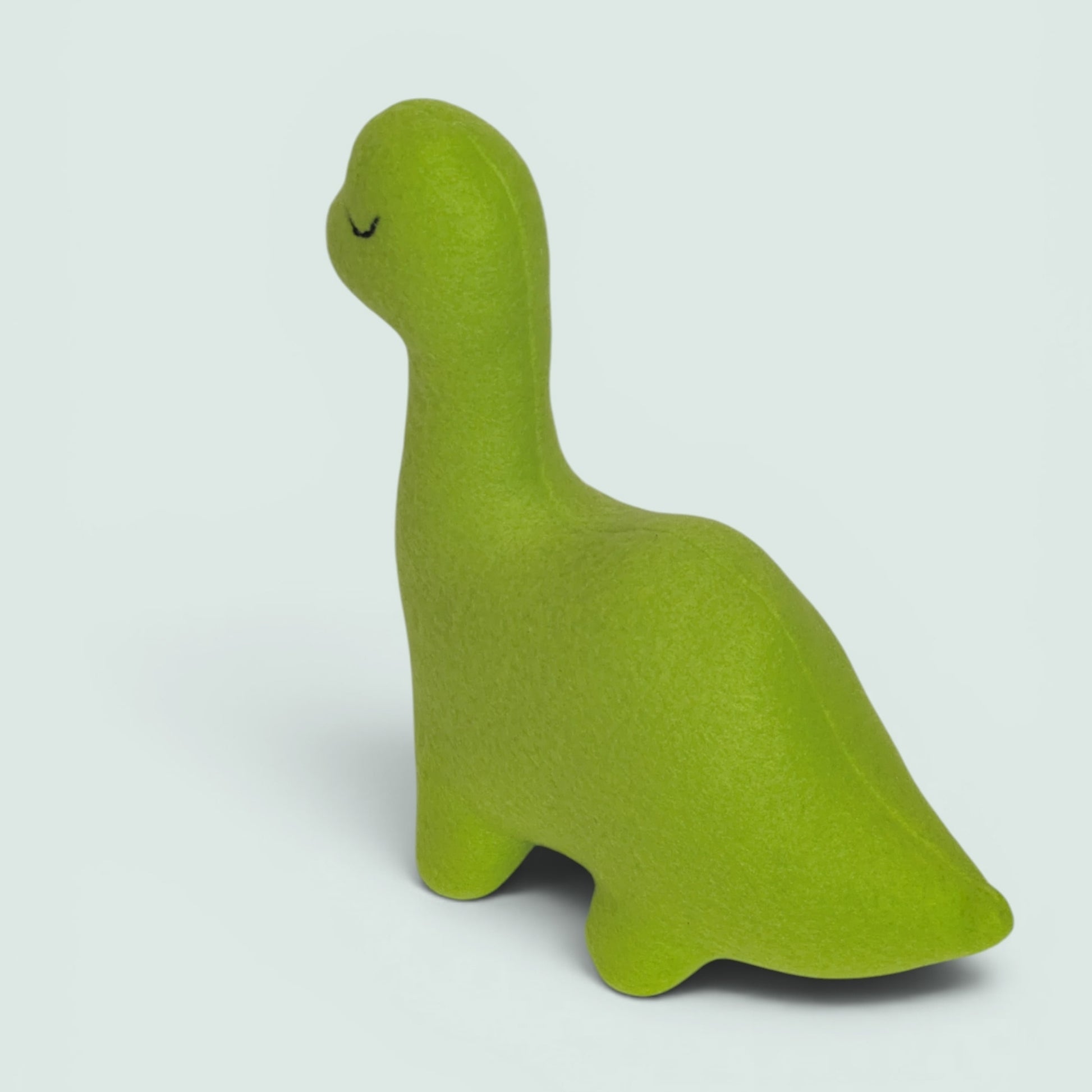 A bright lime green dinosaur-shaped plush toy with a sleeping face, shown on a light gray background.