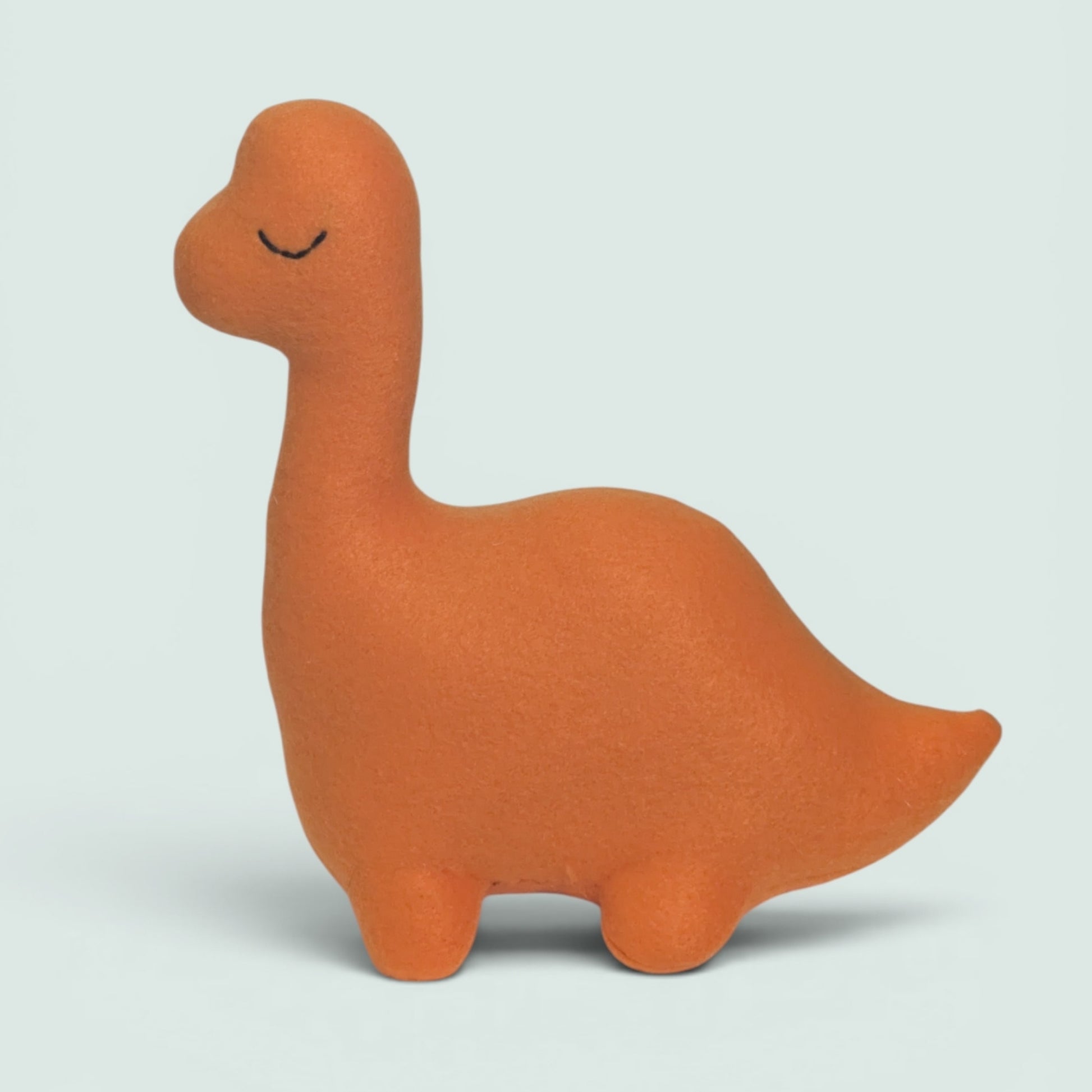 An orange plush dinosaur toy with a long neck and closed embroidered eyes, standing against a light gray background.