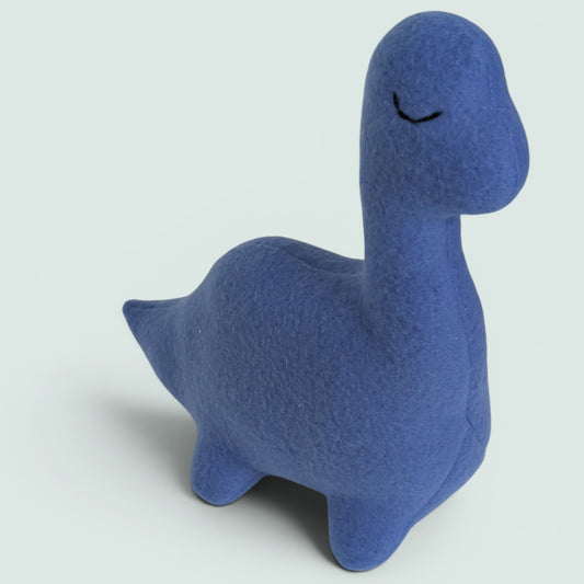 A blue fleece dinosaur toy with a stitched sleeping eye, standing on a light gray background.