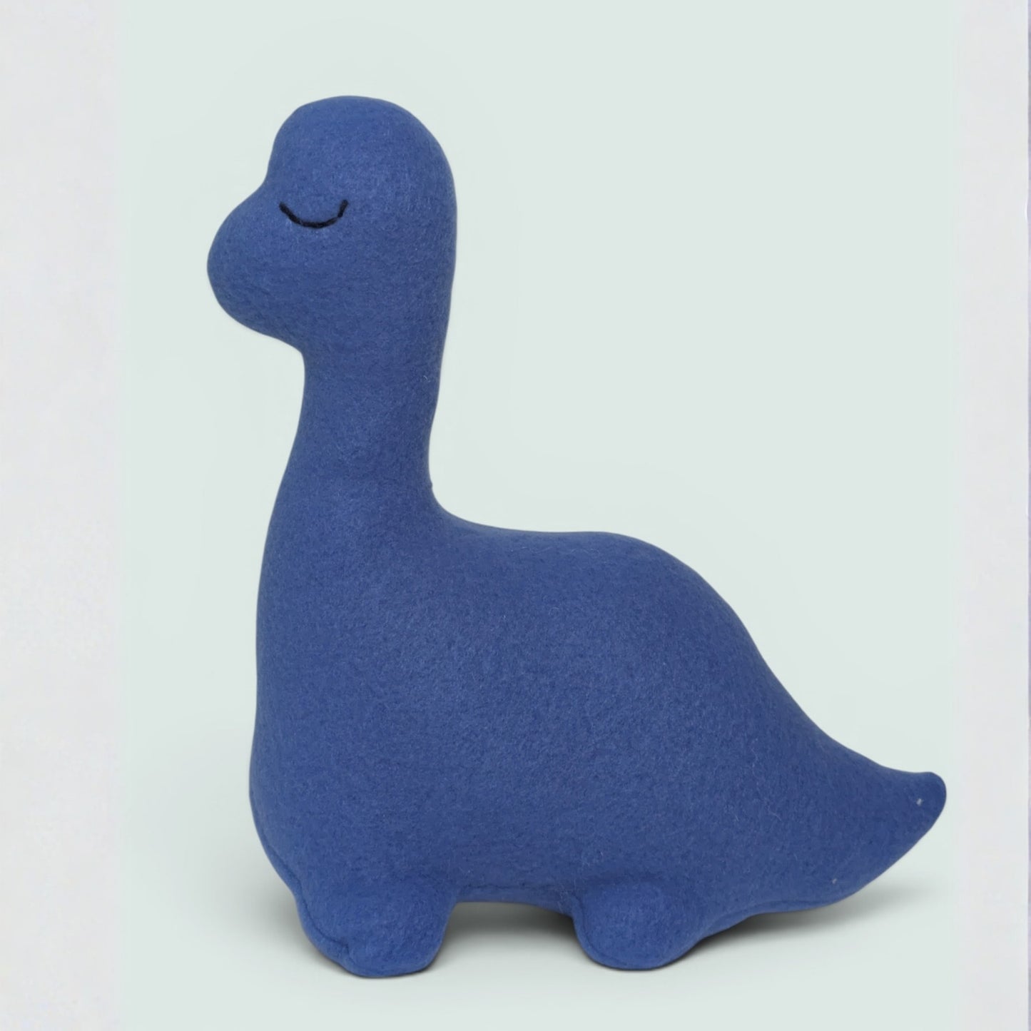 A blue fleece dinosaur plush toy with a long neck and closed embroidered eyes, standing against a light gray background.