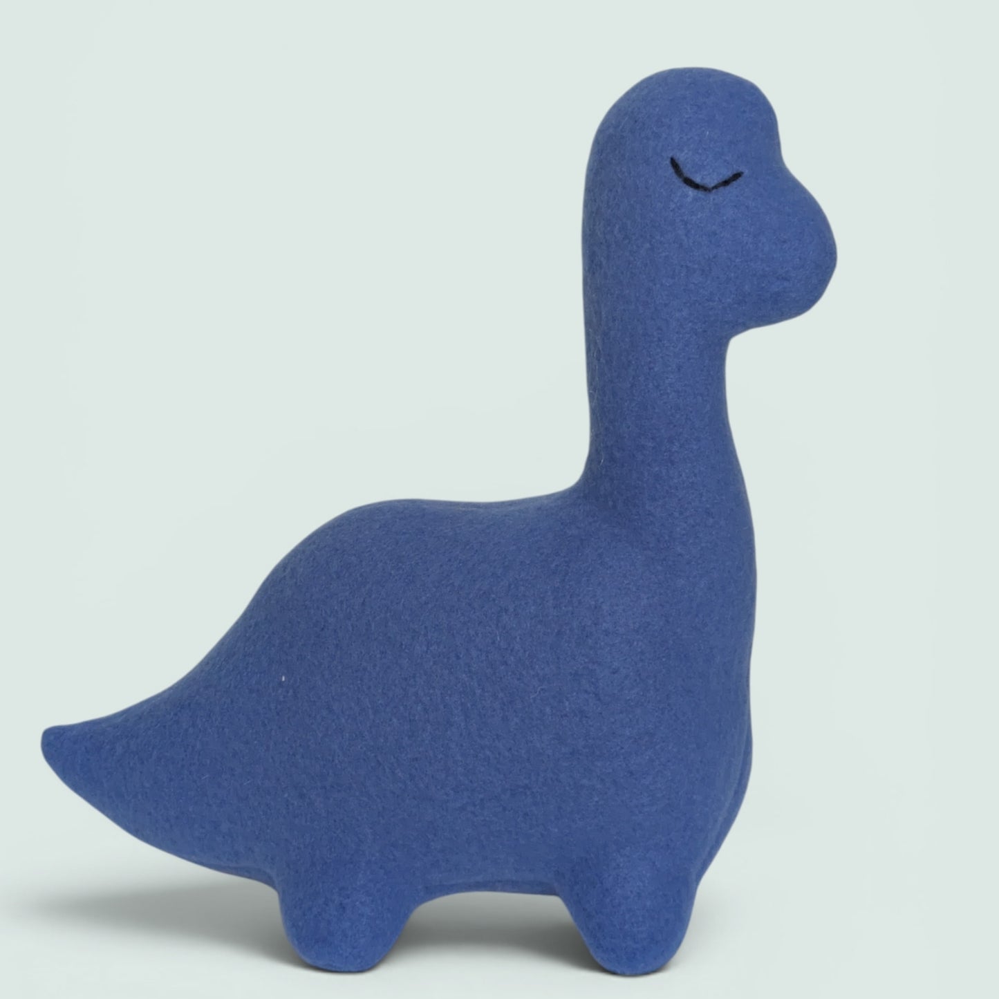 A blue fleece dinosaur toy with a long neck and embroidered closed eyes, shown against a light gray background.
