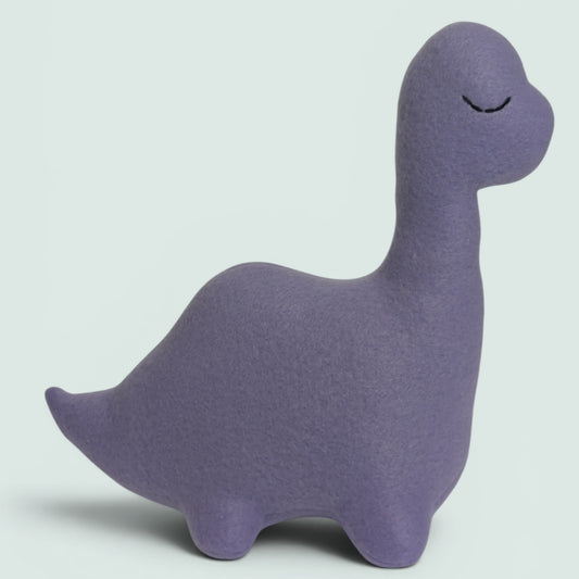 A light purple plush dinosaur toy with a black embroidered eyes, sitting against a soft blue background.