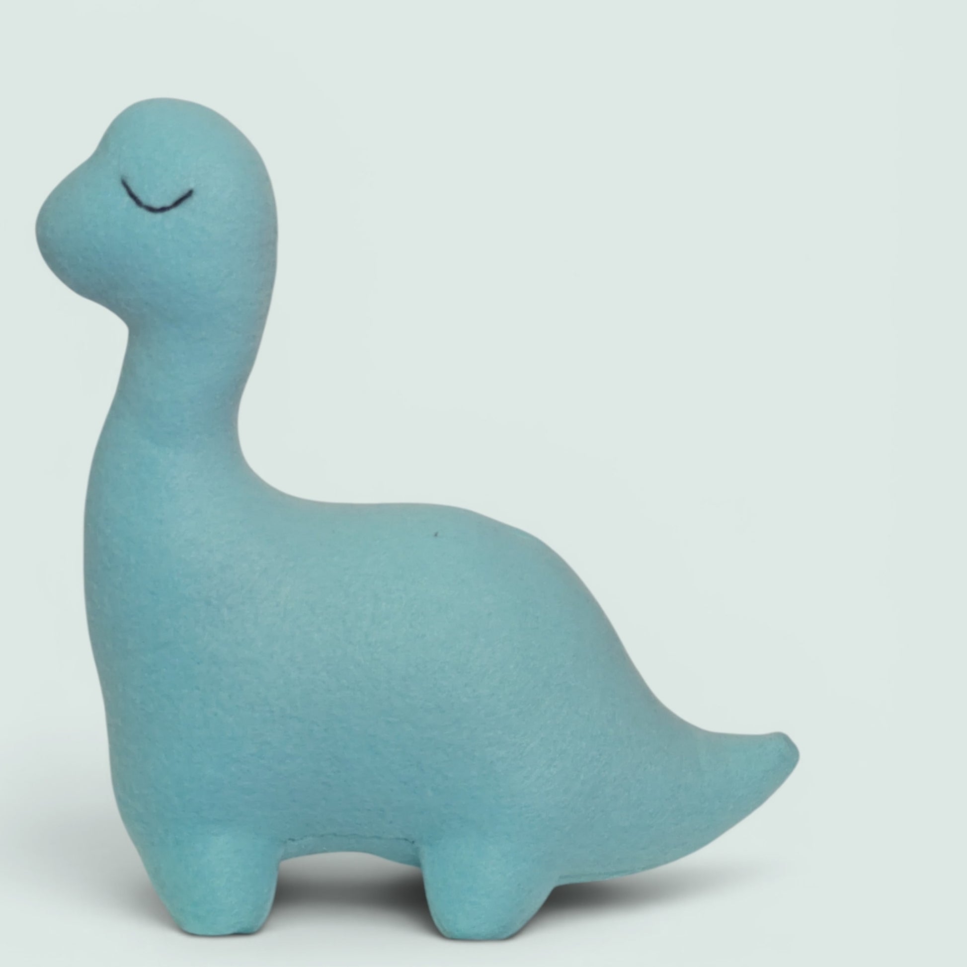 A light blue dinosaur-shaped fleece plush toy with a simple black stitched closed eyes, shown against a solid light gray background.