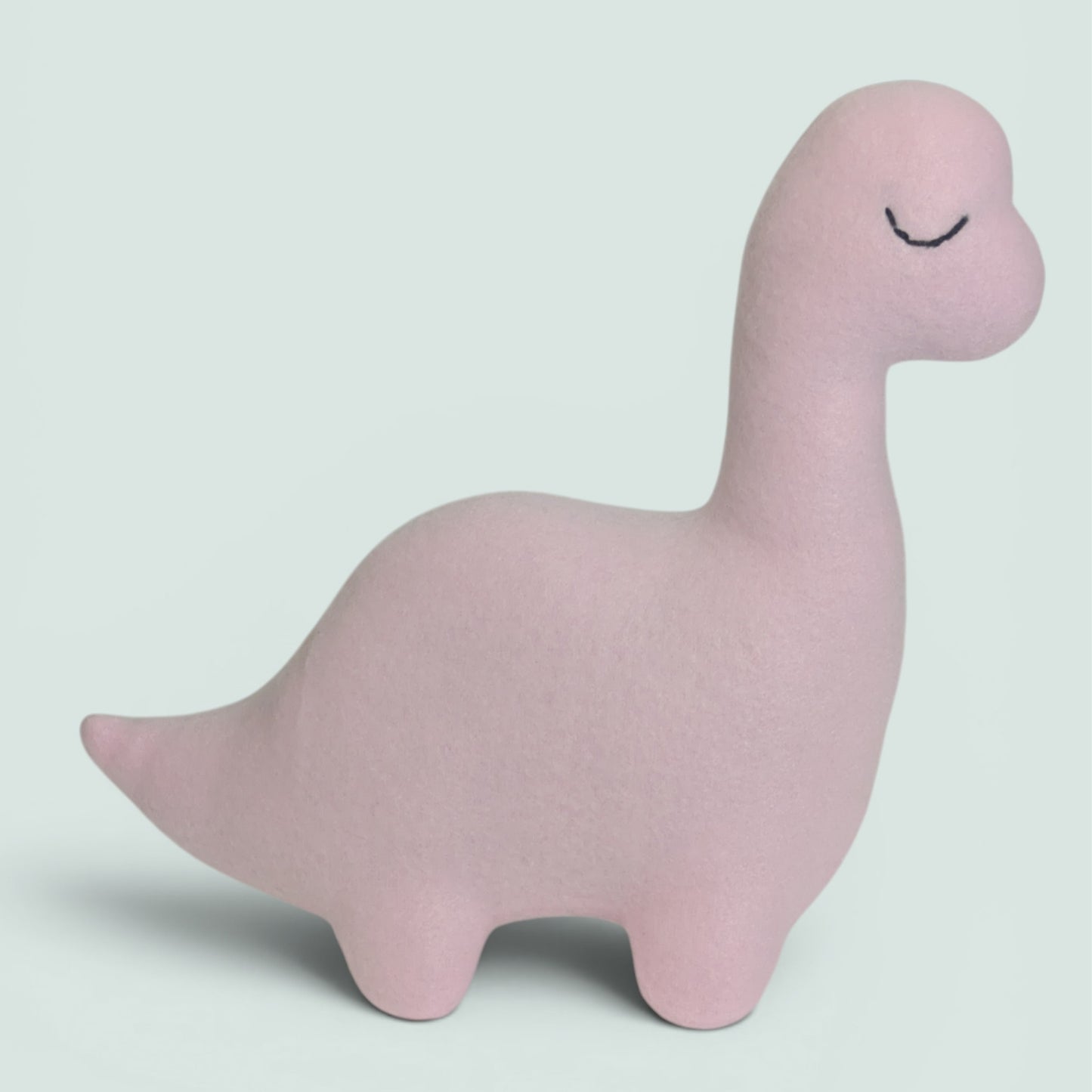 A light pink plush dinosaur toy with a long neck and embroidered closed eyes, standing on a light gray background.