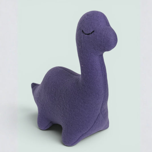 A purple fleece dinosaur toy with a long neck and a stitched closed-eye design, photographed on a light gray background.