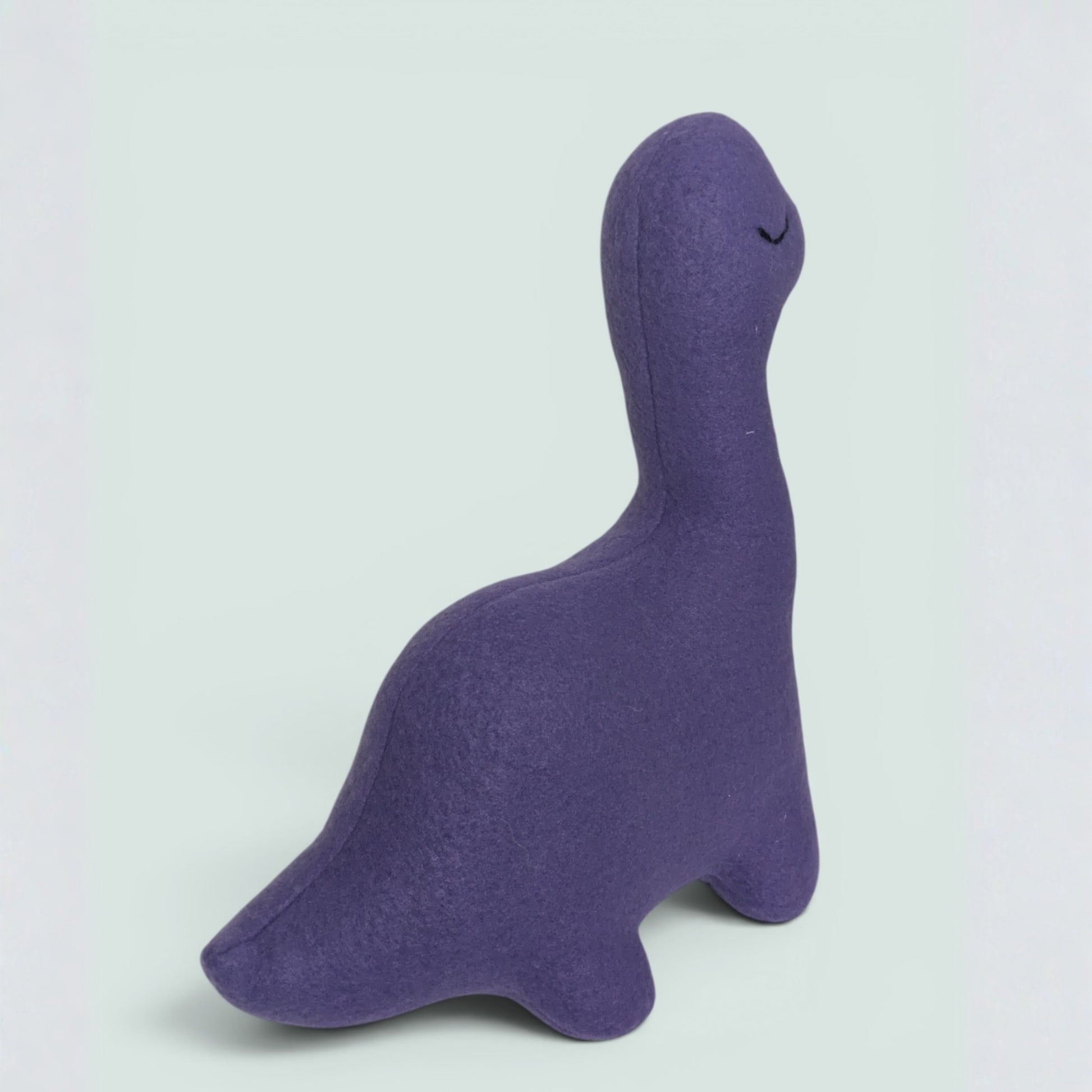 A purple fleece dinosaur plush toy with embroidered closed eyes, shown from a side profile on a light gray background.